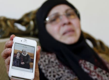 The sister-in-law of Lebanese passenger Randa Daher reacts as she holds her mobile phone displaying a picture of Randa and one of her children at her home in the southern Lebanese village of Srifa July 24, 2014. REUTERS/Ali Hashisho