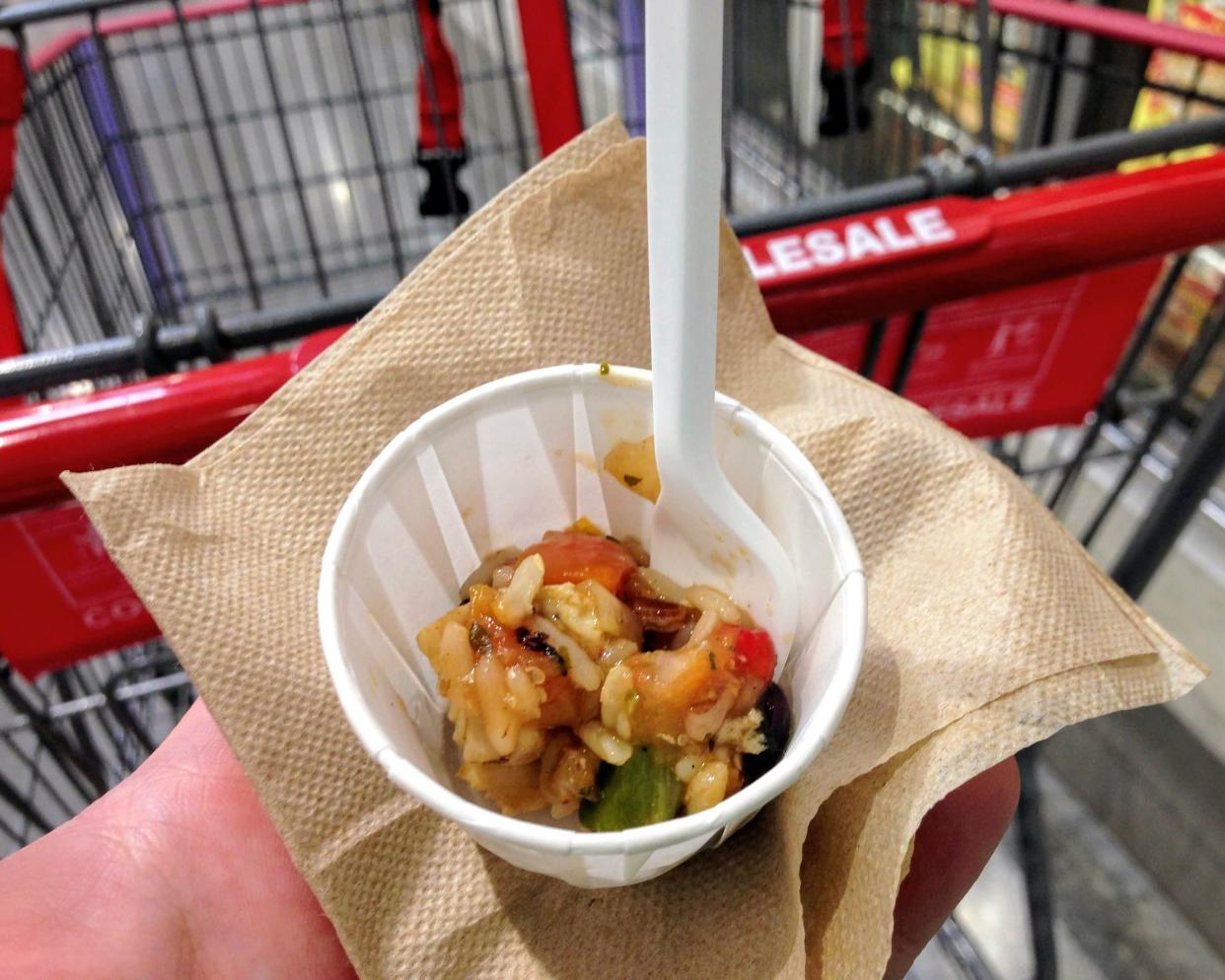 A hand holding a food sample in Costco