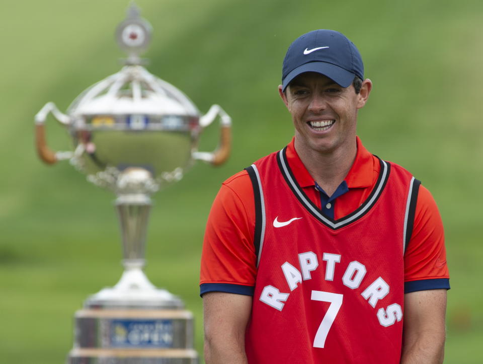 Rory McIlroy laughs as he puts on a Toronto Raptors jersey during the trophy presentation at the Canadian Open golf championship in Ancaster, Ontario, on Sunday, June 9, 2019. (Adrian Wyld/The Canadian Press via AP)