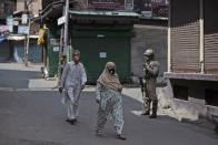 Kashmiris walk past a paramilitary soldier standing guard during curfew in Srinagar, Indian controlled Kashmir, Tuesday, Aug. 4, 2020. Authorities clamped a curfew in many parts of Indian-controlled Kashmir on Tuesday, a day ahead of the first anniversary of India’s controversial decision to revoke the disputed region’s semi-autonomy. Shahid Iqbal Choudhary, a civil administrator, said the security lockdown was clamped in the region’s main city of Srinagar in view of information about protests planned by anti-India groups to mark Aug. 5 as “black day." (AP Photo/Mukhtar Khan)