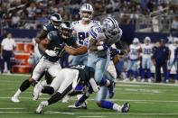 Dallas Cowboys running back Ezekiel Elliott (21) breaks a tackle attempt by Philadelphia Eagles safety Anthony Harris, bottom left, as he sprints to the end zone for a touchdown in the first half of an NFL football game in Arlington, Texas, Monday, Sept. 27, 2021. (AP Photo/Michael Ainsworth)