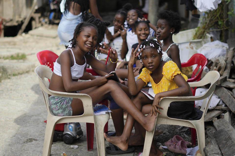 Youths pose for a photo, while doing their homework in an area once home to chop houses, where gangs dismembered enemies, but is now a "humanitarian space" in Buenaventura, Colombia, Wednesday, Aug. 16, 2023. Buenaventura’s “humanitarian space” is a former red zone transformed with the help of human rights groups as a place for community, safety and activism. (AP Photo/Fernando Vergara)