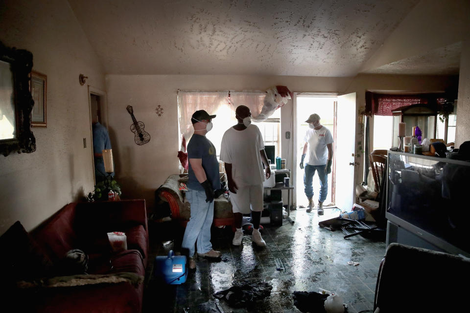People on cleanup duty look around a damaged property.
