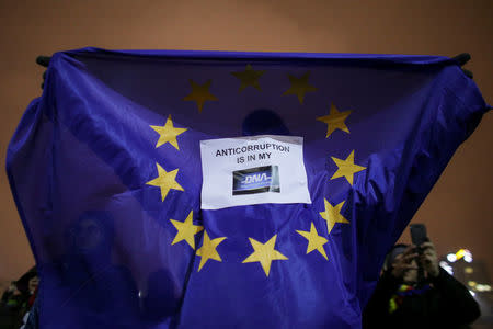 A man holds up an European Union flag that has the message "Anticorruption is in my DNA" while people protest a government move to call for the sacking of the country's chief anti-corruption prosecutor in Bucharest, Romania, February 25, 2018. Inquam Photos/Octav Ganea via REUTERS