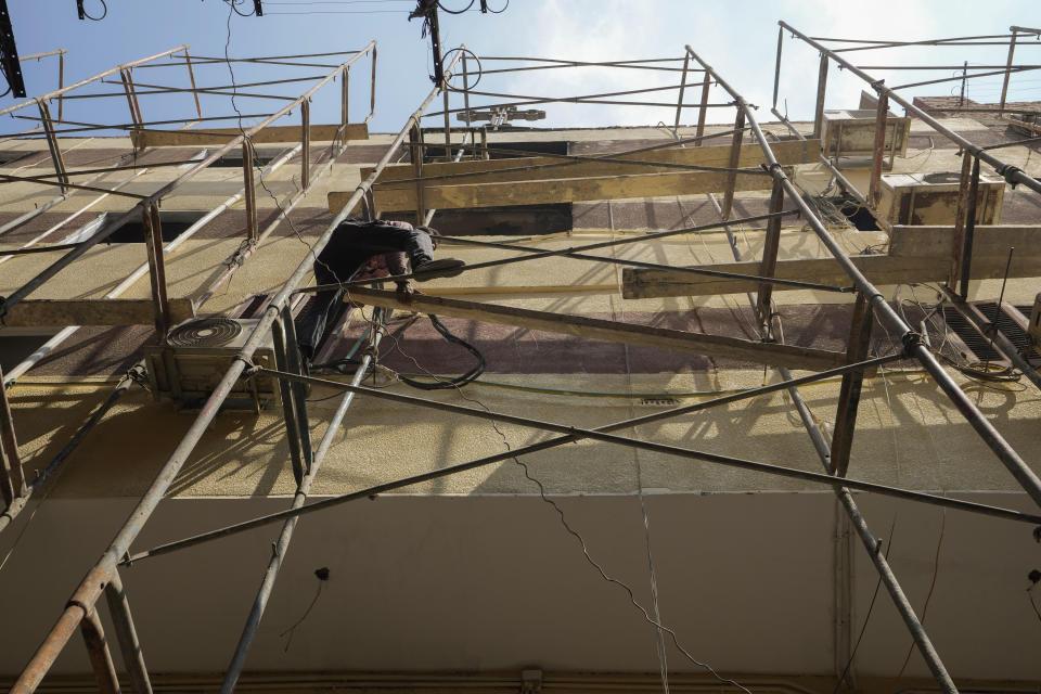 A worker installs scaffolding at the Abu Sefein church, a day after a fire killed over 40 people and injured at least 14 others, in the densely populated neighborhood of Imbaba, in Cairo, Egypt, Monday, Aug. 15, 2022. (AP Photo/Amr Nabil)