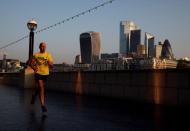 FILE PHOTO: A man runs at sunrise, with the City of London financial district in the background