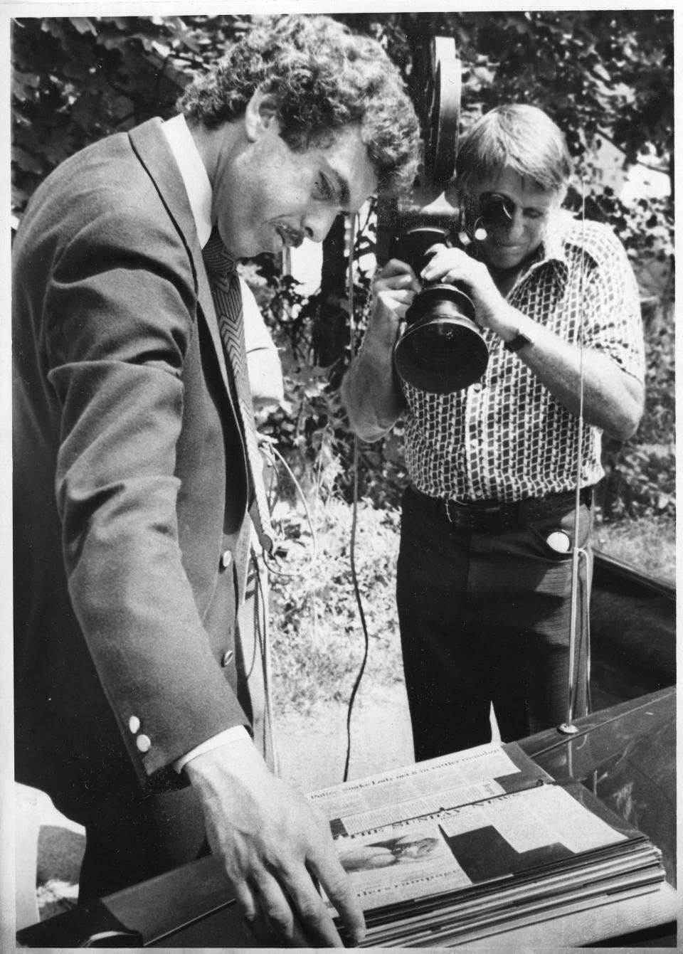 Arnold Diaz of Channel 2 CBS; and cameraman looking over Ridgewood News scrapbook of snake emergence.