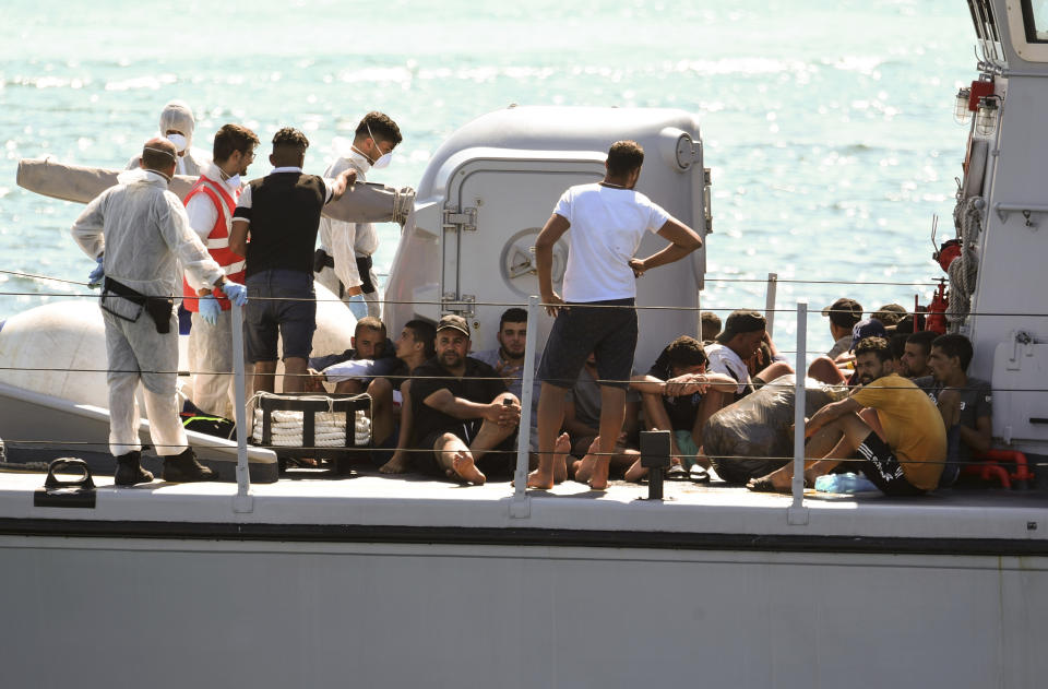 Migrants rescued by an Italian Finance police patrol boat sit in the ship as it docks in the port of the Sicilian island of Lampedusa, southern Italy, Monday, Aug. 19, 2019. According to reports, a small vessel carrying more than 30 migrants was intercepted in the waters off Lampedusa and rescued by the Finance Police. 107 migrants are still on board a Spanish NGO Open Arms vessel anchored off Lampedusa because Italian Interior Minister Matteo Salvini won't let private rescue boats into his nation's ports. (AP Photo/Salvatore Cavalli)