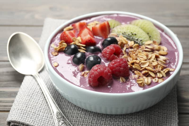 Delicious acai smoothie with fruits served on grey wooden table, closeup