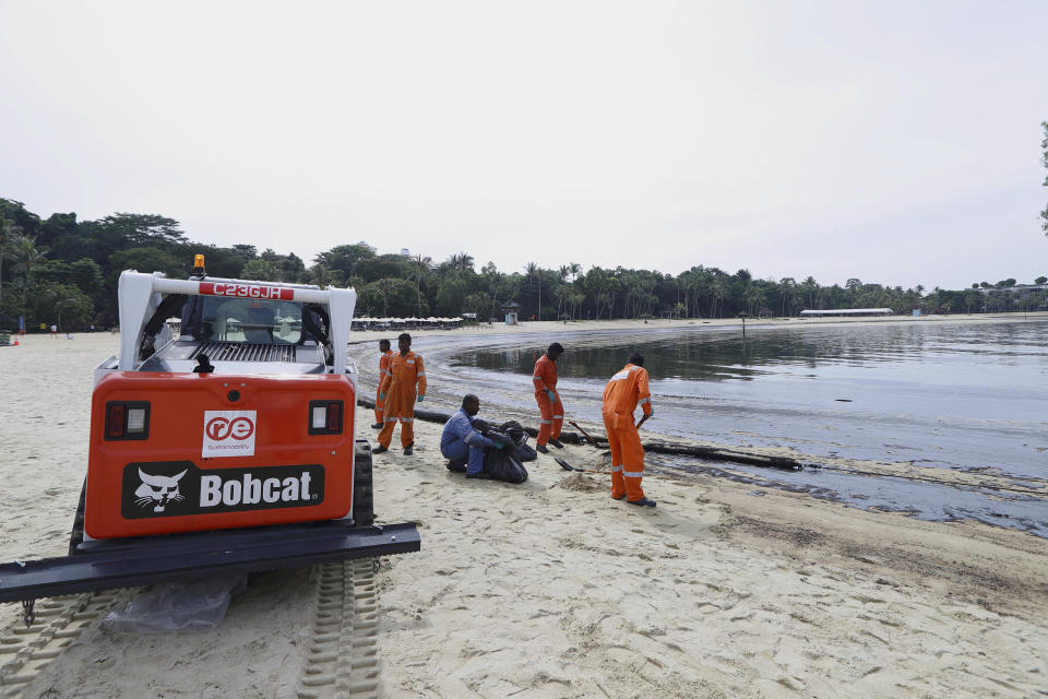 Workers clean oil spill along Sentosa's Tanjong Beach area in Singapore, Sunday, June 16, 2024. An oil spill caused by a dredger boat hitting a stationary cargo tanker has blackened part of Singapore’s southern coastline, including the popular resort island of Sentosa, and sparked concerns it may threaten marine wildlife. (AP Photo/Suhaimi Abdullah)