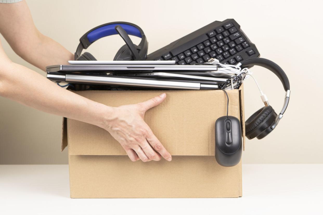 Woman hands holding cardboard box full old used computers, phones, tablets, gadget devices for recycling. Planned obsolescence, e-waste, donation, electronic waste for reuse and recycle concept.