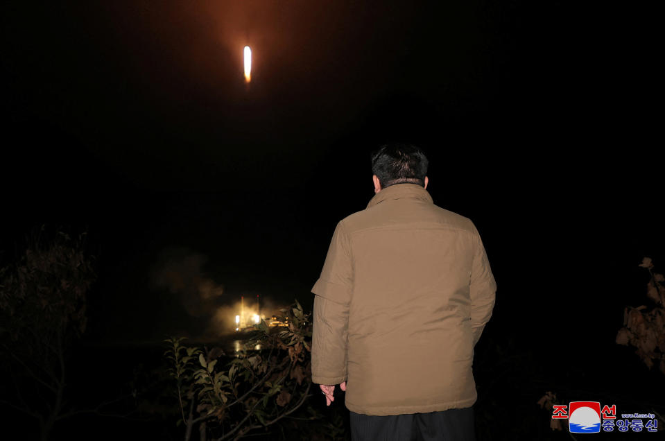 Kim Jong Un looks on as a rocket carries a spy satellite. 