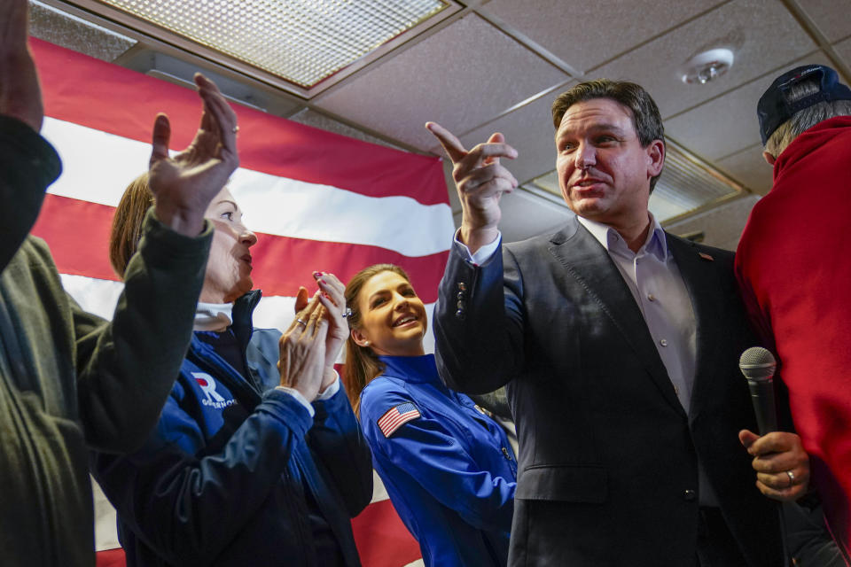 Republican presidential candidate Florida Gov. Ron DeSantis, right, takes the microphone after being introduced at an event in West Des Moines, Iowa, Saturday, Jan. 13, 2024. Also on stage with him are Iowa Gov. Kim Reynolds, left, and DeSantis wife, Casey DeSantis. (AP Photo/Pablo Martinez Monsivais)