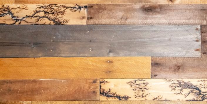 Wood planks have unusual fractal lightning patterns via high voltage wood burning.