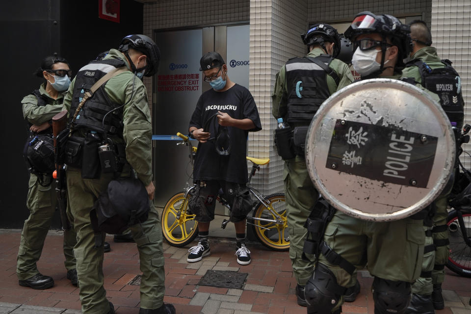 A pedestrian's credentials are checked by police in Causeway Bay, Hong Kong, during China's National Day on Thursday, Oct. 1, 2020. The popular shopping district of Causeway Bay saw a heavy police presence on the Oct. 1 National Day holiday despite low protester turnout. (AP Photo/Kin Cheung)