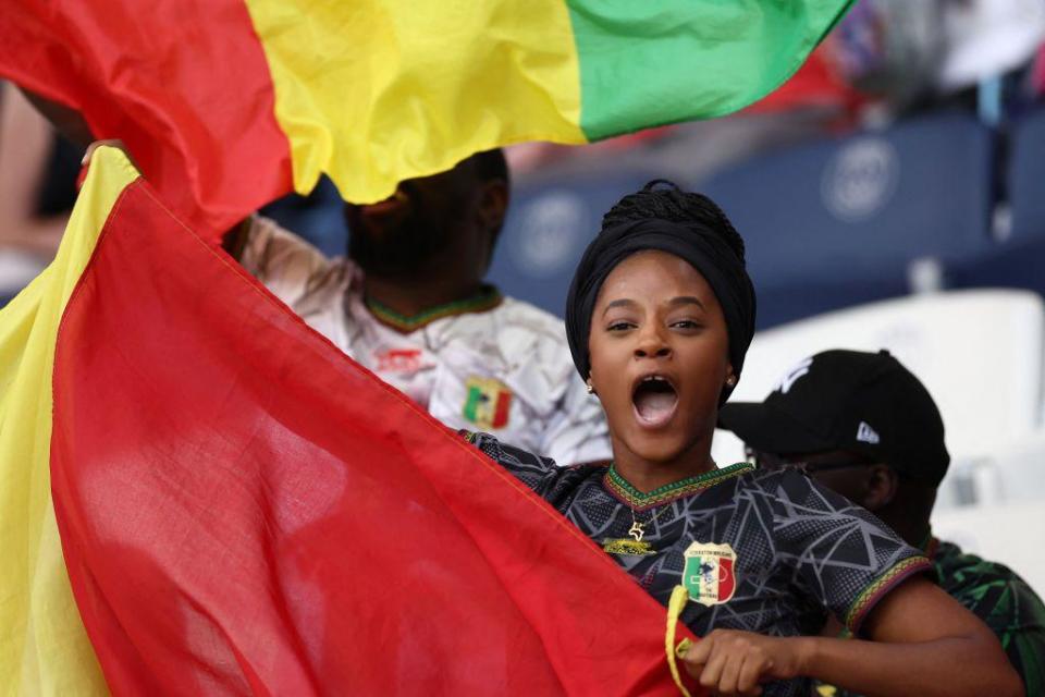 A woman watching in the stands waves the Malian flag at a stadium in Paris, France - Thursday 25 July 2024