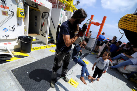 A migrant child plays with a member of the crew on board the MV Aquarius rescue ship run by SOS Mediterranee organisation and Doctors Without Borders during a search and rescue (SAR) operation in the Mediterranean Sea, off the Libyan Coast, August 12, 2018. Picture taken August 12, 2018. REUTERS/Guglielmo Mangiapane