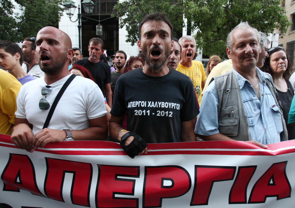 Protesting steelworkers chant anti-government slogans outside Labor Ministry as they hold banner reads ''Strike'' on Monday, July 23, 2012. Police forced an end to a strike lasting nearly four months at a steel plant near Athens last week. The action triggered a political spat between the country's new conservative-led government and left wing opposition parties ahead of a new visit to Athens this week by international debt inspectors. (AP Photo/Thanassis Stavrakis)