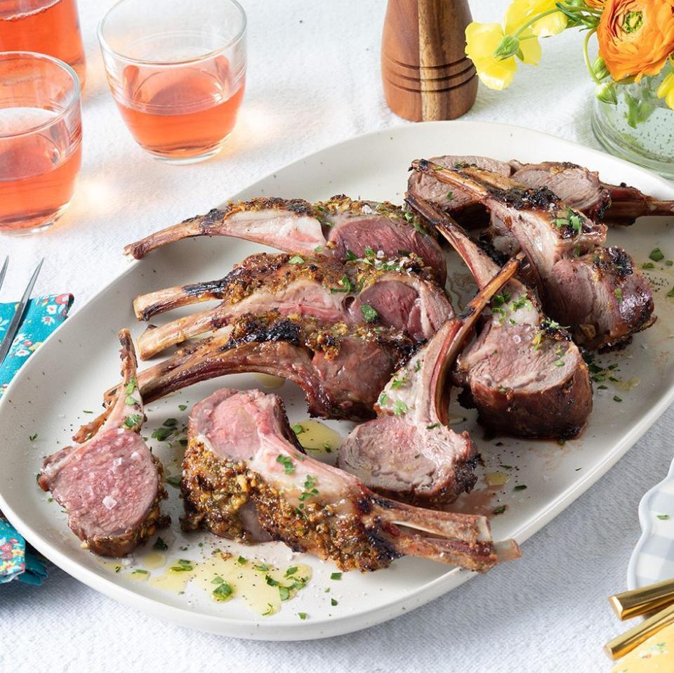 rack of lamb on white platter glasses of wine in back