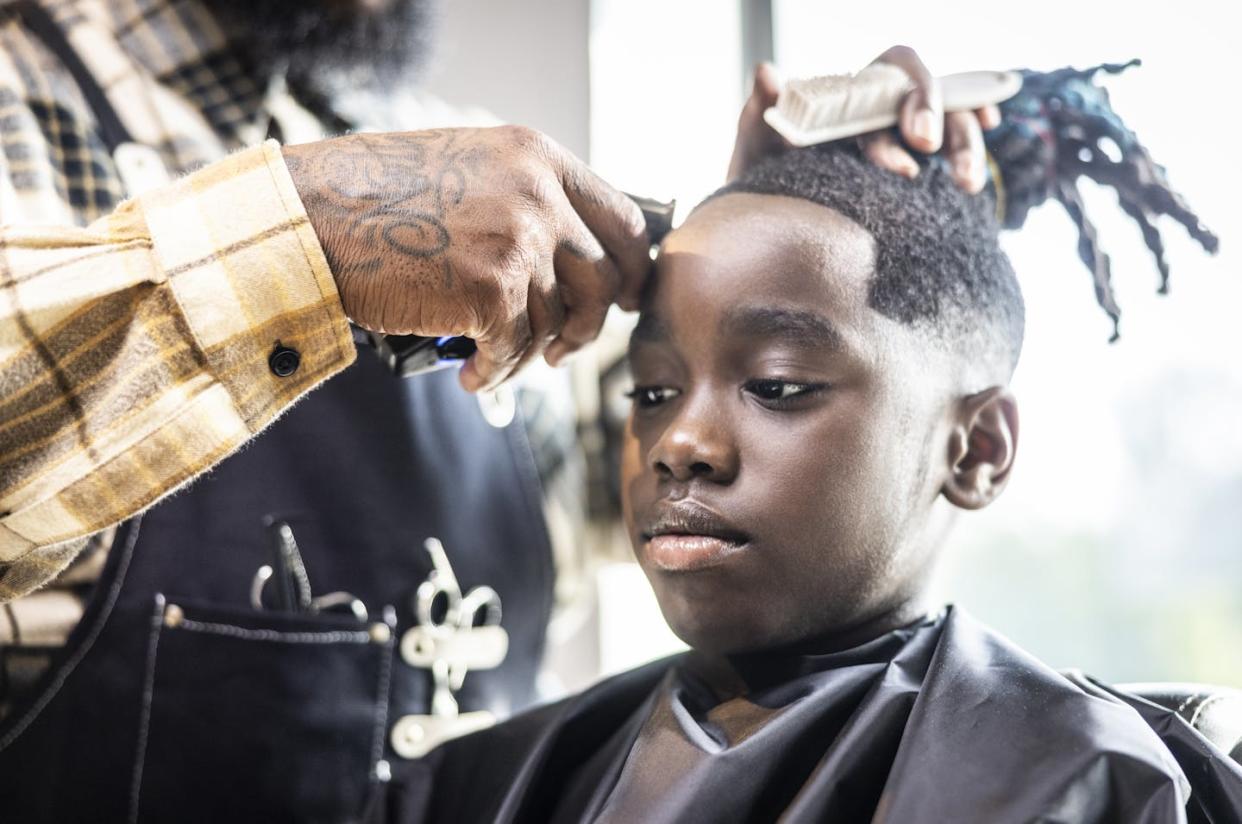 America's schools don't always welcome cultural expression. <a href="https://www.gettyimages.com/detail/photo/barber-cutting-young-boys-hair-in-barbershop-royalty-free-image/1717468327?phrase=black+boy+dread+locs&adppopup=true" rel="nofollow noopener" target="_blank" data-ylk="slk:MoMo Productions via Getty Images;elm:context_link;itc:0;sec:content-canvas" class="link ">MoMo Productions via Getty Images</a>