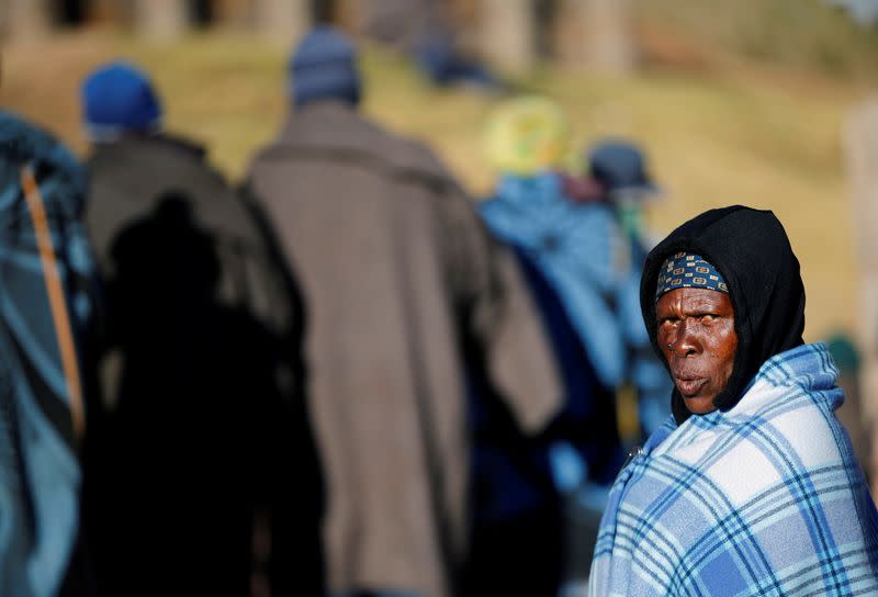 Woman looks on as locals queue to cast their ballots during the national elections at Hatimo Village