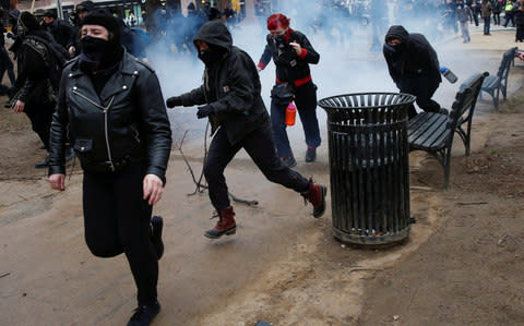 Activists race after being hit by a stun grenade while protesting against U.S. President-elect Donald Trump on the sidelines  - Credit: Adrees Latif/Reuters