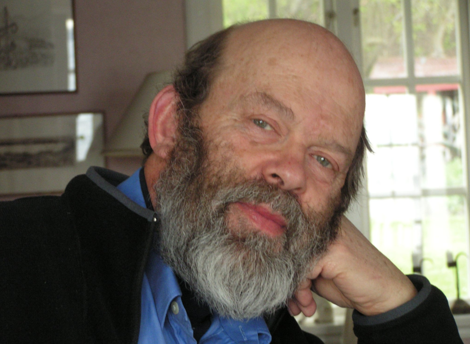 Rolf Castor pictured with a beard and bald head looking into the camera.