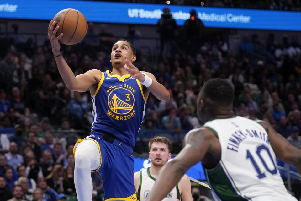 Golden State Warriors guard Jordan Poole (3) goes up for a shot between Dallas Mavericks' Dorian Finney-Smith (10) and Luka Doncic, rear, in the second half of an NBA basketball game in Dallas, Thursday, March, 3, 2022. (AP Photo/Tony Gutierrez)