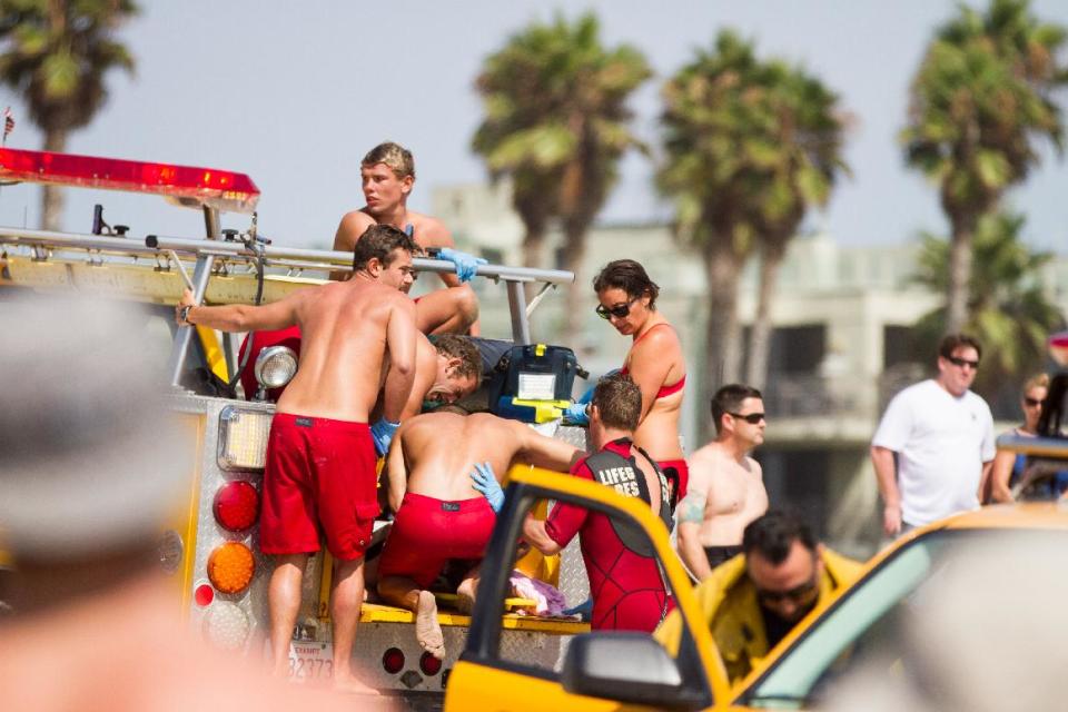CORRECTS SPELLING Lifeguards assist a person who was in the water Sunday July 27, 2014 in Los Angeles. Authorities said lightning struck 14 people, leaving two critically injured, as rare summer thunderstorms swept through Southern California on Sunday. (AP Photo/Steve Christensen)