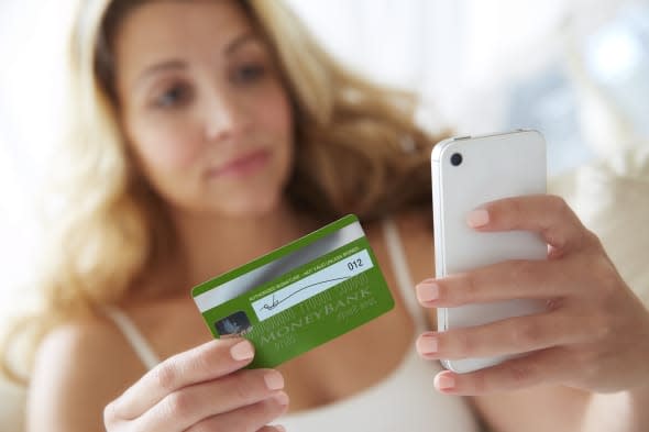 Woman using smart phone mobile device with credit card to make online purchase.