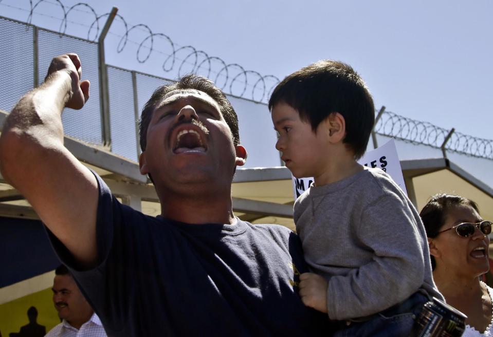 Daniel Rodriguez holds three-year-old Matthew Huert as he leads a chant for members of the group Border Dreamers and other supporters of an open border policy who marched to the United States border Monday, March 10, 2014, in Tijuana, Mexico. (AP Photo/Lenny Ignelzi)