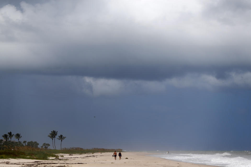 People walk on a largely deserted beach of the Atlantic Ocean on the barrier island in Vero Beach, Fla., Sunday, Sept. 1, 2019. The barrier island is under a voluntary evacuation today and a mandatory evacuation tomorrow in preparation for the possibility of Hurricane Dorian making landfall. (AP Photo/Gerald Herbert)