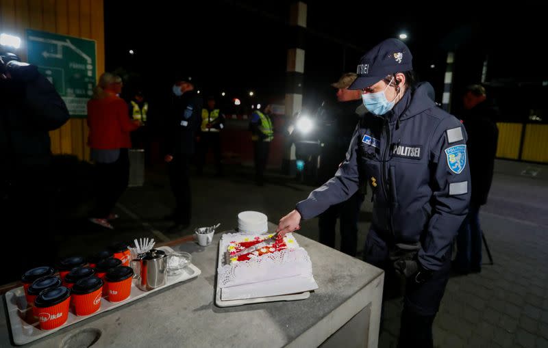 An Estonian police officer wearing a protective face mask cuts a cake at border crossing point in Ikla