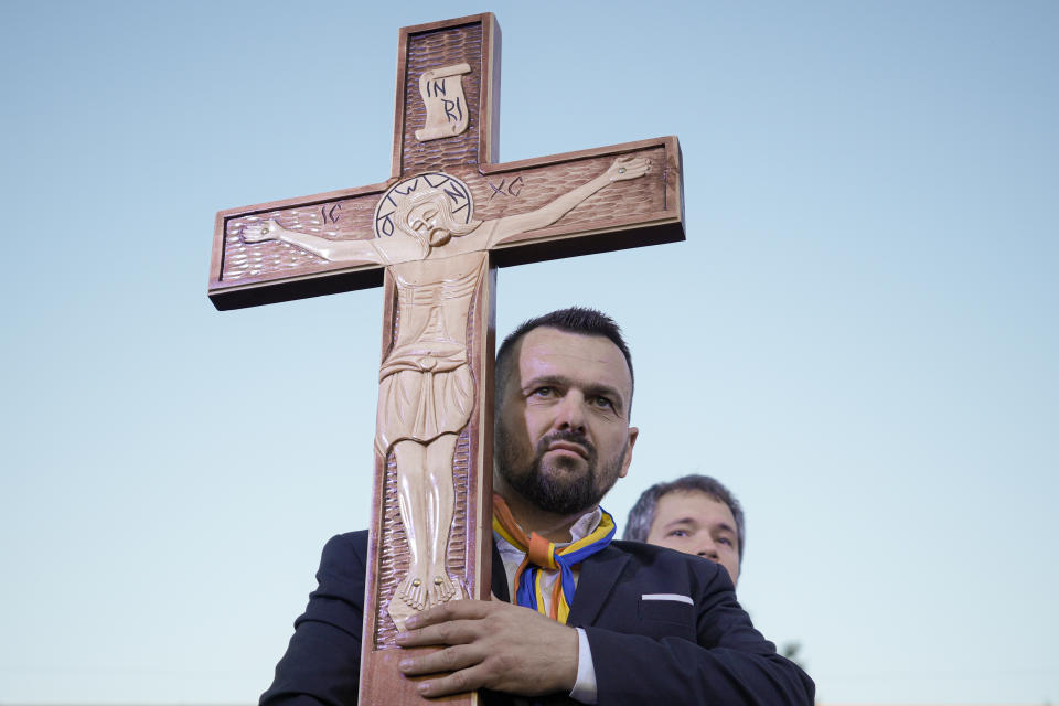 A man holds a wooden cross during an anti-government and anti-vaccination protest organised by the far-right Alliance for the Unity of Romanians or AUR, in Bucharest, Romania, Saturday, Oct. 2, 2021. Thousands took to the streets calling for the government's resignation, as Romania reported 12,590 new COVID-19 infections in the past 24 hour interval, the highest ever daily number since the start of the pandemic. (AP Photo/Vadim Ghirda)
