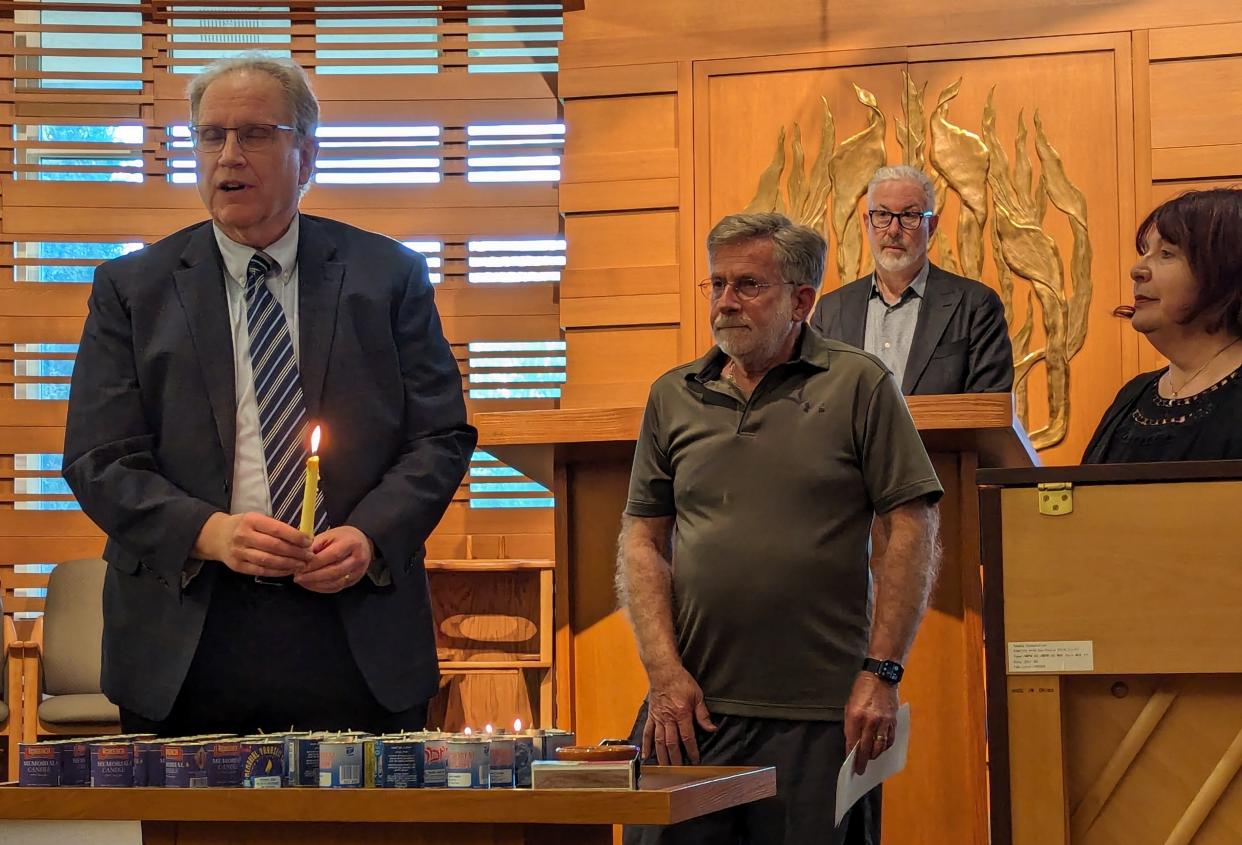 Hazzan Bruce Braun of Shaaray Torah Synagogue, left, Dr. Marvin Boren and Peggy Stabholtz light memorial candles at a community Yom HaShoah service at Beit Ha'am in Canton. John Strauss, back, hosted the event.