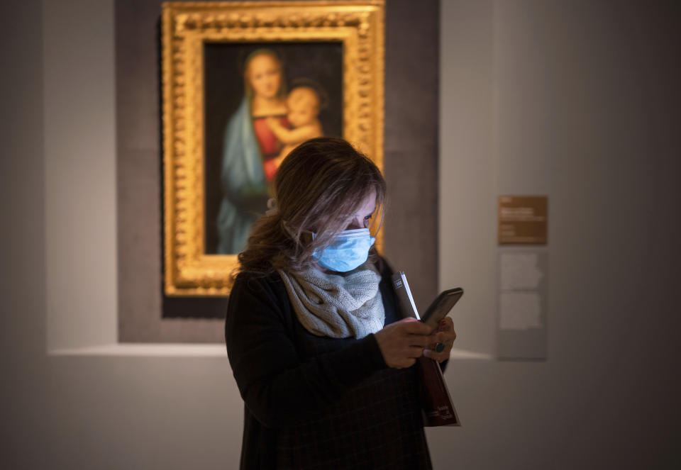 A woman wearing a mask attends a press preview of Raphael's exhibition in Rome, Wednesday, March 4, 2020. The paintings, drawings and sketches in the most ambitious assemblage ever of Raphael works in an exhibition, more than even the Renaissance superstar had in his workshop at one time, are collectively insured for 4 billion euros ($.4 billion), against the likes of theft or vandalism. But no money can guarantee that Italy’s outbreak of coronavirus, the largest in Europe, won’t play havoc with the three-month run in Rome of the art world’s eagerly-awaited blockbuster. (AP Photo/Domenico Stinellis)