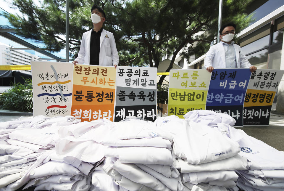 Doctors hold signs criticizing the government's medical policy at a hospital in Suwon, South Korea, Wednesday, Aug. 26, 2020. Health officials in South Korea called on thousands of striking doctors to return to work as the country counted its 13th straight day of triple-digit daily jumps in coronavirus cases. The sign reads: "Let's criticize the rapid administration and we oppose policies that ignore filed opinions and ensure working conditions." (Hong Hae-in/Yonhap via AP)