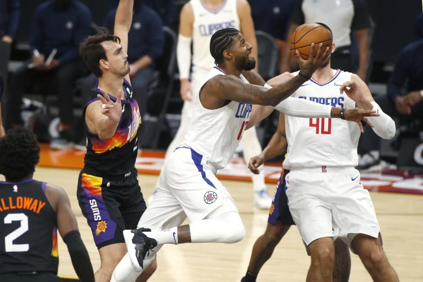 Los Angeles Clippers forward Paul George, center, drives to the basket past the defense.