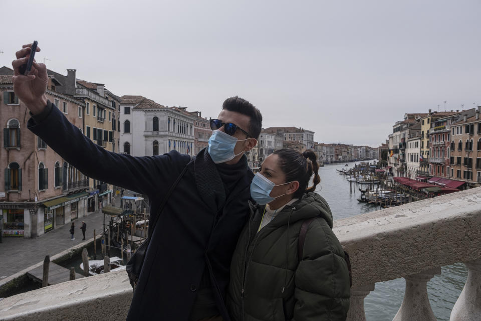 VENICE, ITALY - MARCH 06: Tourists with protective face masks take a selfie on the Rialto Bridge on March 06, 2020 in Venice, Italy. Venice is deserted because of COVID-19, yesterday, March 5, a third person died in the city due to the COVID-19 virus. The latest Civil Protection bulletin talks about 3,858 COVID-19 positives, 148 people died and 414 have recovered in Italy. (Photo by Stefano Mazzola/Awakening/Getty Images)