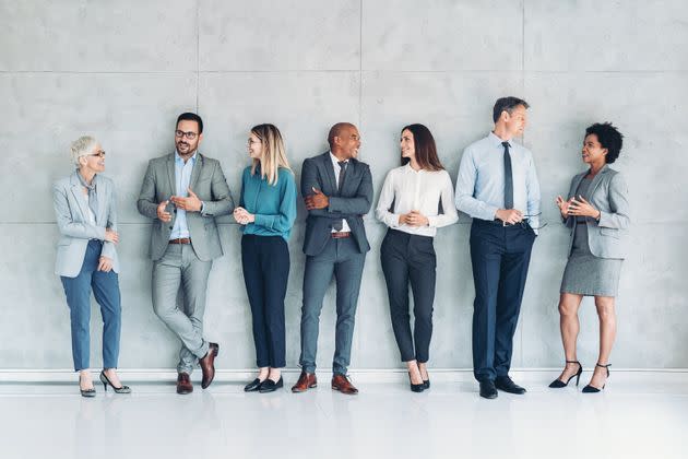 Multi-ethnic group of people in formal businesswear standing and talking (Photo: pixelfit via Getty Images)