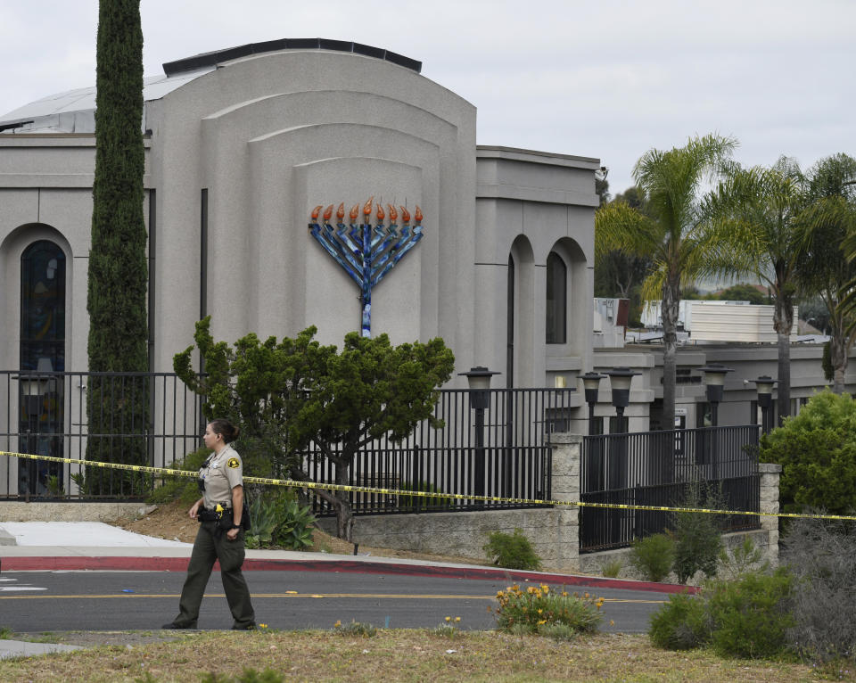 FILE - In this Sunday, April 28, 2019 file photo, a San Diego county sheriff's deputy stands in front of the Chabad of Poway synagogue, in Poway, Calif. A 19-year-old nursing student who opened fire at the California synagogue in April didn't have a valid hunting license, which is the only way someone under 21 who isn't in the military or law enforcement can legally buy a weapon under state law. The California Fish and Wildlife Department said Wednesday, Aug. 14, 2019, that John T. Earnest was issued a hunting license, but it had not gone into effect yet. It’s unclear how Earnest bought the gun. (AP Photo/Denis Poroy, File)