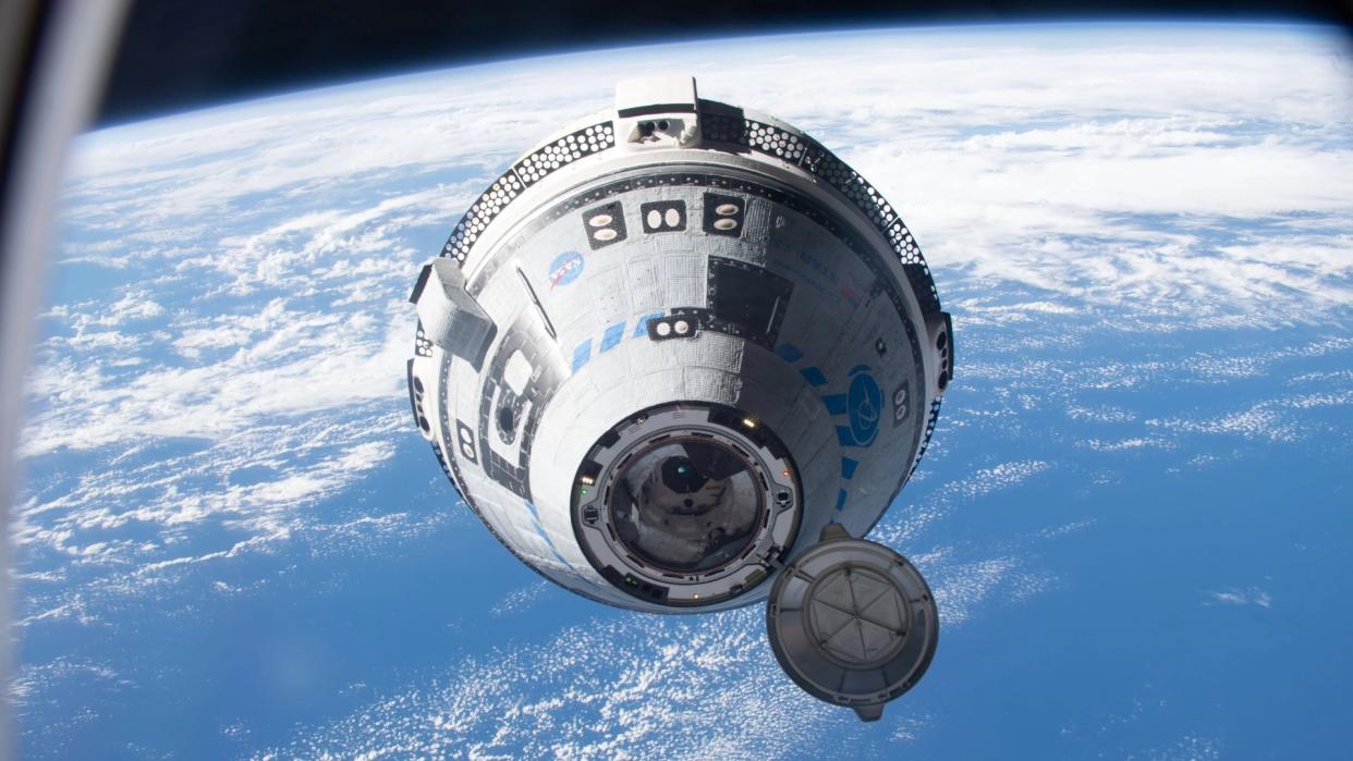 A grey-and-blue cone-shaped spacecraft in space above the Earth. 