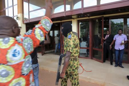 A member of the presidential guard walks past anti-coup protesters at the Laico hotel in Ouagadougou, Burkina Faso, September 20, 2015. REUTERS/Joe Penney