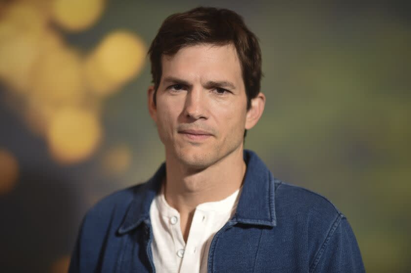 Ashton Kutcher in a white shirt and dark blue jacket