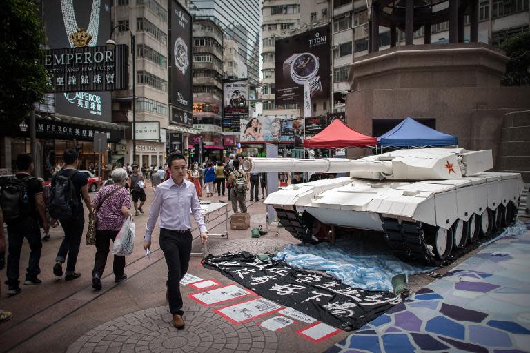 Pedestrians walk past a tank replica displayed to symbolise China's June 4, 1989, Tiananmen military crackdown, in Hong Kong on June 3, 2014