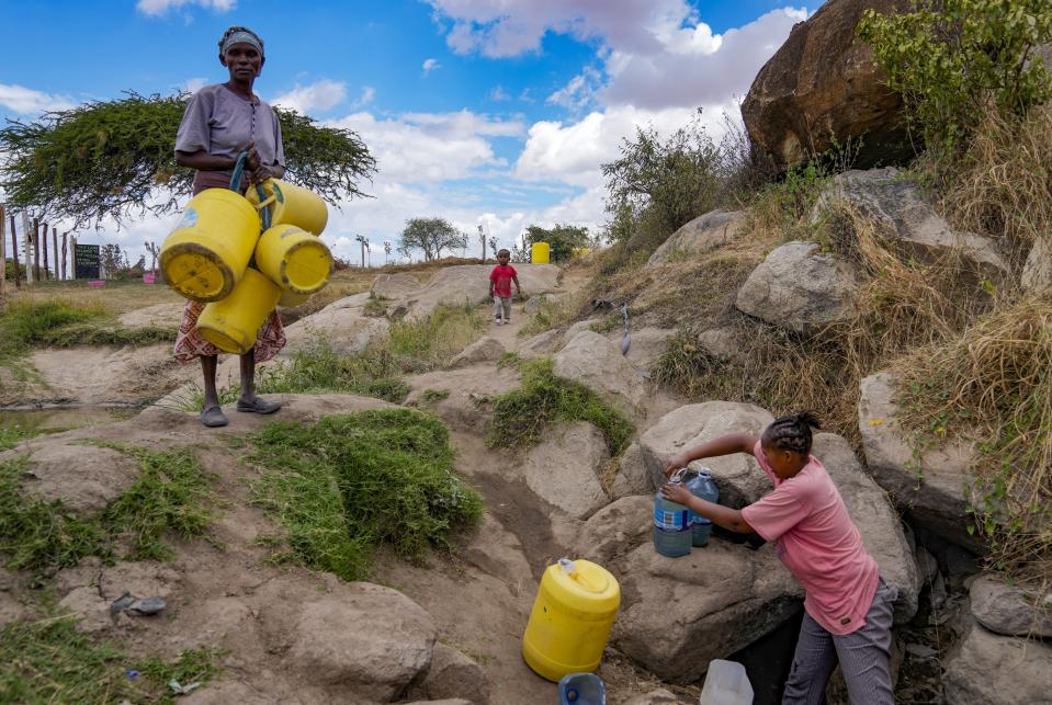 Joyce Ngui, left, fetches water in Athi River, Machakos county, Kenya, Oct. 17, 2023. (AP Photo/Brian Inganga)