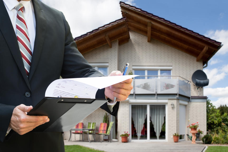 Midsection Of A Man Checking Documents Standing Near House With Solar Panels On Roof