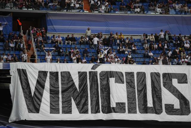 Spectators sit behind a banner with the name of Real Madrid's Vinicius Junior prior to a Spanish La Liga soccer match between Real Madrid and Rayo Vallecano at the Santiago Bernabeu stadium in Madrid, Spain, Wednesday, May 24, 2023. (AP Photo/Manu Fernandez)