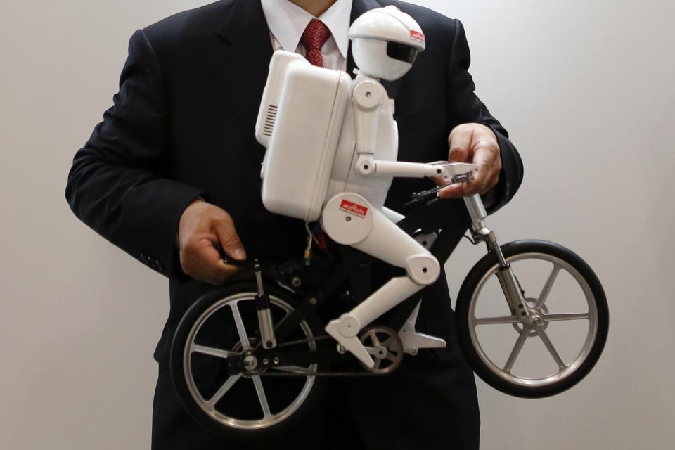 Murata Manufacturing Co Ltd President Murata poses with his company's bicycle-riding robot