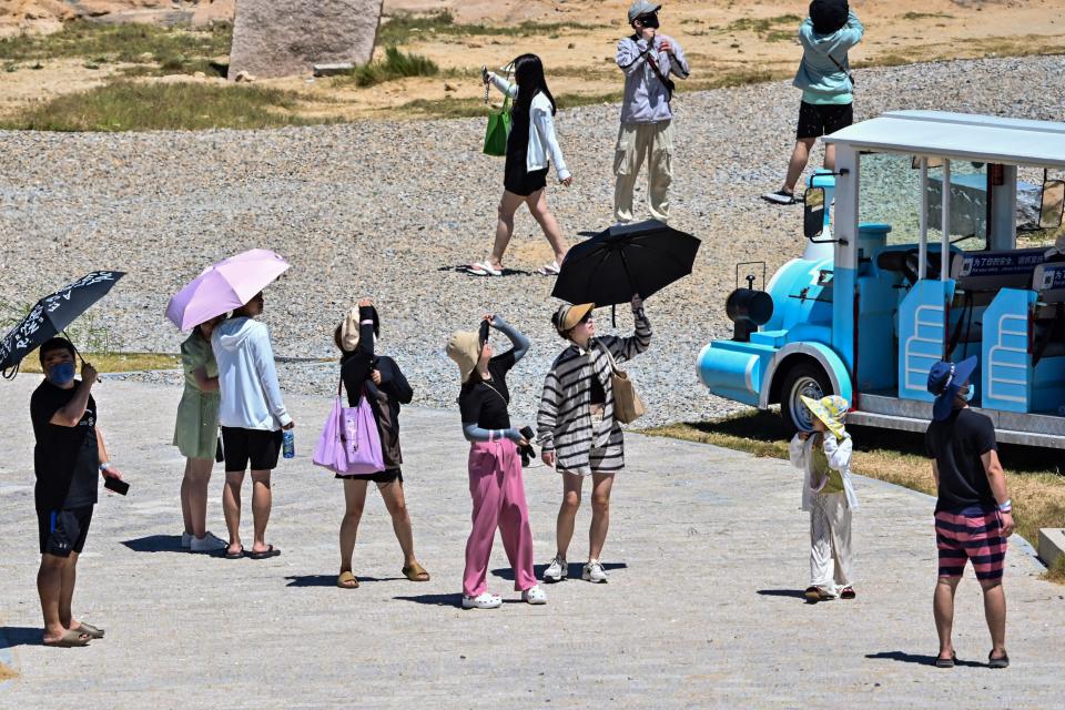 Tourist look up as a Chinese military jet flies over Pingtan island, one of mainland China’s closest point from Taiwan, in Fujian province on 5 August 2022 (AFP via Getty Images)